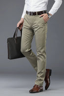 Person wearing beige pants and brown shoes holding a black briefcase on a gray background, Obroi
