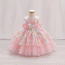 A pink toddler girl's party dress displayed on a mannequin. The sleeveless dress features a tiered tulle skirt in light pink and a bodice decorated with 3D floral appliques in shades of pink, yellow, green, and blue, Obroi