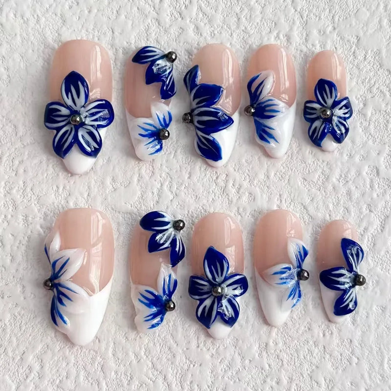 Nail art with blue floral designs on a textured white background