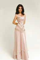 A woman modeling a long, sleeveless formal gown in a pale blush pink color with intricate lace and sequin embellishments. The brand name 'Obroi' is printed in black text in the top-left corner against a plain light gray studio background.