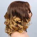 A side profile view of a woman wearing a short, wavy wig with a dark brown root transitioning into warm golden blonde highlights at the ends, set against a plain light gray background, Obroi