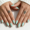 Close-up of hands with light green nail polish on a white background, Obroi