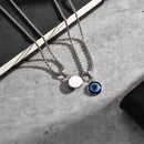Two necklaces with round pendants on a textured surface, Obroi