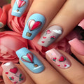 Nails with heart and balloon design held against pink roses, Obroi