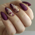 Hand with purple and gold floral nail art on a neutral background, Obroi