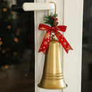 A gold metal bell Christmas hanging ornament decorated with a red ribbon featuring gold snowflakes, a pine sprig, and a small pinecone, hanging from a white door handle, Obroi