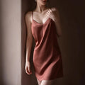 Woman wearing a pink slip dress against a plain wall, Obroi
