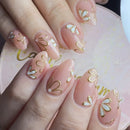Nails with gold and white floral designs on a pink background, Obroi