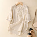 White blouse with lace details on a hanger against a beige background, Obroi