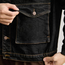 Close-up of a person wearing a black denim jacket with a buttoned pocket, Obroi
