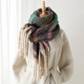 Multicolored scarf with tassels draped over a white coat on a wooden stand, Obroi