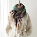 Multicolored scarf with tassels draped over a white coat on a wooden stand, Obroi