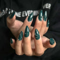 Close-up of hands with teal nail polish against a black background, Obroi