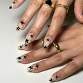 Close-up of hands with star-themed nail art on a neutral background, Obroi