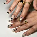 Close-up of hands with star-themed nail art on a neutral background, Obroi