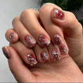 Hand with red and silver nail art on a neutral background, Obroi