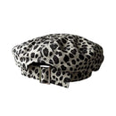 A structured flat cap with a black and off-white leopard print pattern, featuring a matching fabric chin strap with a silver metal buckle, Obroi