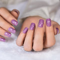 Close-up of hands with purple nail polish on a white background, Obroi