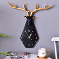 Decorative wall clock with deer antlers on a gray wall, next to a mug and books, Obroi
