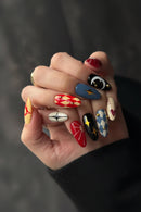 Hand with intricately designed nails featuring various patterns and colors, Obroi