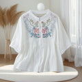 White blouse with floral embroidery on a mannequin against a neutral background, Obroi