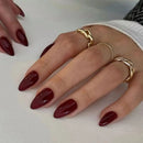 Close-up of hands with red nail polish and gold rings on a white background, Obroi