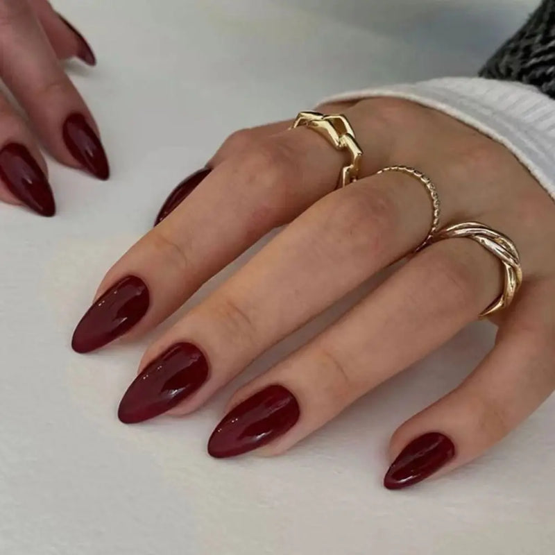 Close-up of hands with red nail polish and gold rings on a white background, Obroi