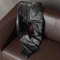 Black leather pants on a brown leather couch with a gray textured wall background, Obroi