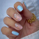 Hand with light blue nail polish and decorative gold and pink design on a white background,Obroi