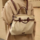 Beige backpack with brown straps worn by a person in a beige coat, Obroi
