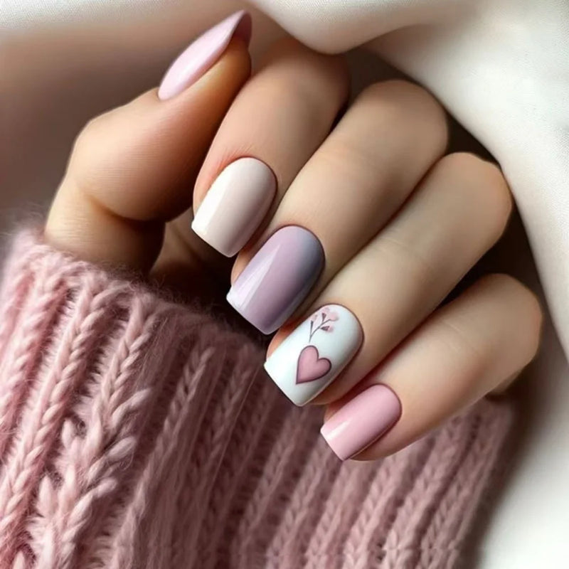 Close-up of a hand with pastel nail polish and a heart design, wearing a pink knitted sweater, Obroi