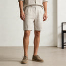 Person wearing beige shorts and shoes in a minimalistic setting, Obroi