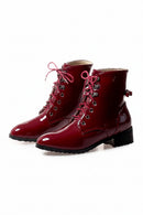 Pair of red patent leather boots with pink laces on a white background, Obroi