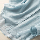 Light blue button-up shirt on a beige surface, Obroi