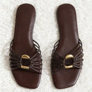 Pair of brown sandals with gold accents on a textured white surface, Obroi