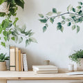 Decorative wall with leaf decals, books on a shelf, and plants, Obroi