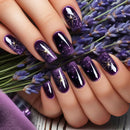 Hand with purple and black galaxy-themed nail design holding lavender flowers, Obroi