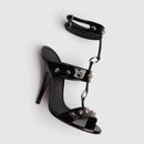 Black high-heeled sandal with studded details on a white background, featuring the brand 'Obroi'.