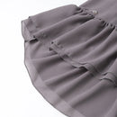 Close-up of a gray ruffled skirt or dress fabric with layered tiers and a small white brand tag near the waistband, shown on a white background, Obroi