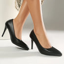 Black high-heeled shoes worn by a person on a neutral background, Obroi