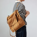 Person wearing a striped sweater with a tan backpack on a plain background, Obroi