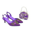 Obroi Purple shoes with gold embellishments and matching handbag on a white background