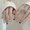 Close-up of hands with decorative nail art and rings on a neutral background, Obroi