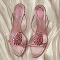 Pair of pink sandals with embellishments on a soft white fabric background, Obroi