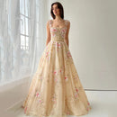 Woman wearing a floral beige evening gown in a softly lit room, Obroi