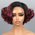 A short wavy wig with dark black roots and deep burgundy ombre ends, styled on a mannequin head against a solid gray background. A black label overlay at the bottom displays the text 'Obroi' and a cursive watermark 'Obroi' is visible across the center.