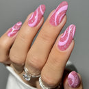 Nails with pink and white swirled design on a neutral background, Obroi