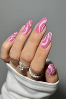 Nails with pink and white swirled design on a neutral background, Obroi