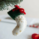 Christmas stocking ornament with red bow hanging on a tree branch, Obroi