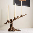Bronze candle holder with three candles on a neutral background